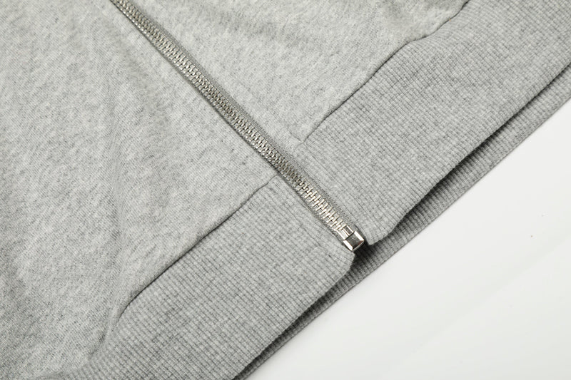 Close-up of light gray hoodie hem and zipper at the ribbed waistband