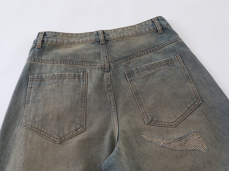 Back pocket view of vintage wash jeans with distressed knee detail visible at edge