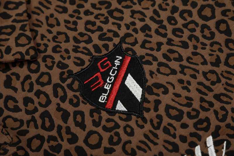 Close-up of a brown leopard print polo tee with black, red and white embroidered Seakoff script patch