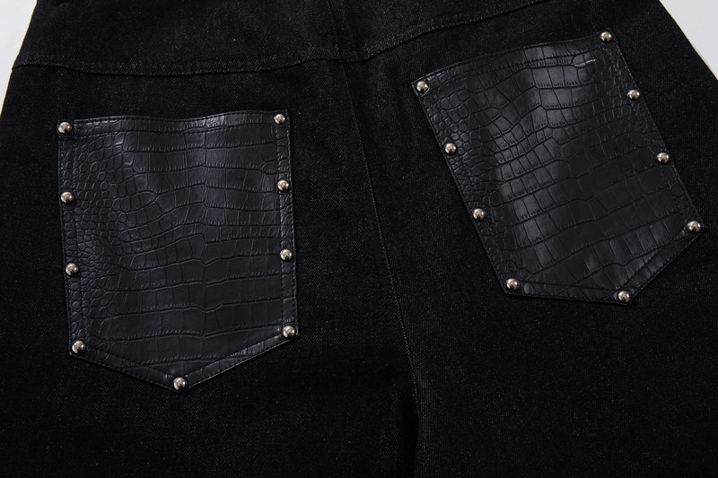 Close-up of two back pockets on black denim pants with crocodile-textured panel inserts and rivets