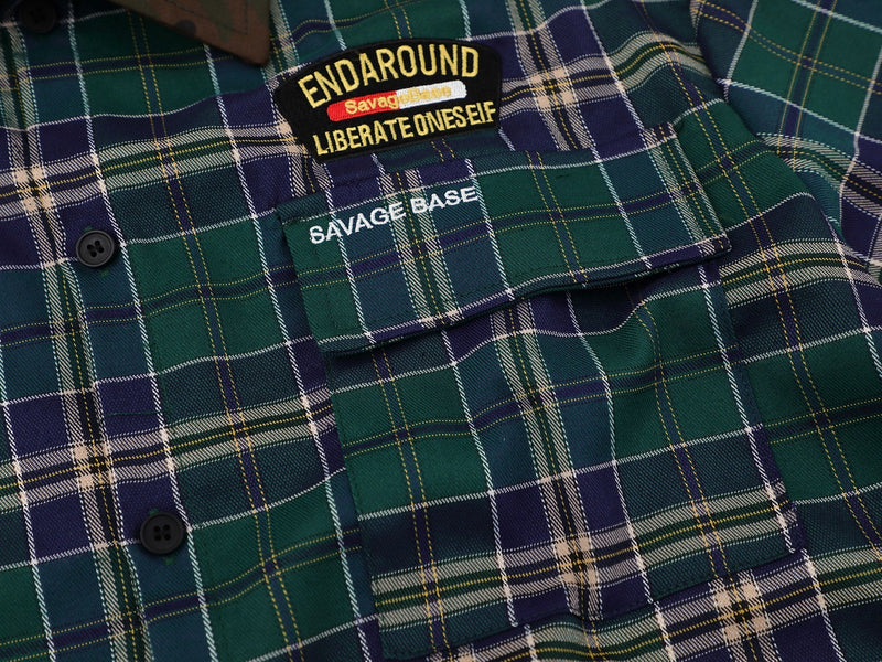 Green and navy plaid shirt with buttoned pocket and embroidered Savage Base patch on the chest