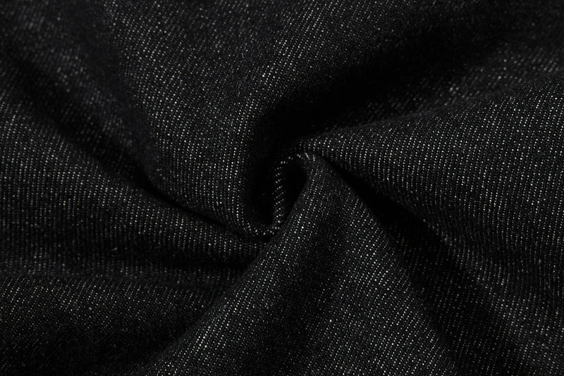 Close-up of black denim fabric texture with soft folds and sheen