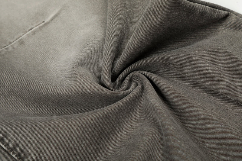 Close-up of grey washed denim fabric with soft folds and fine diagonal twill texture