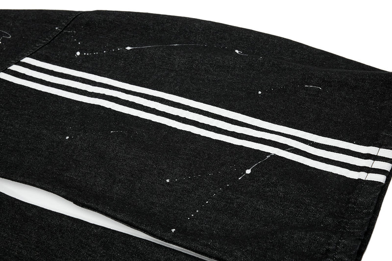 Black jeans leg with white triple side stripes and scattered paint splatter