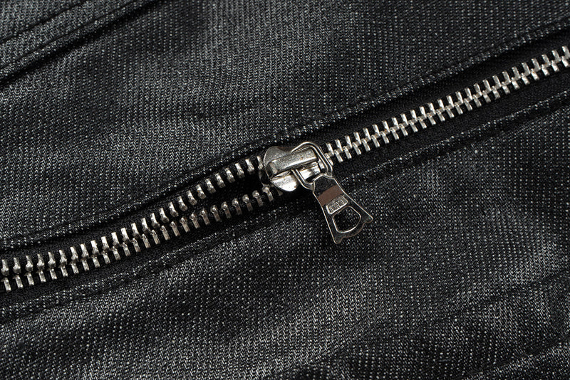 Close-up of silver zipper pull on black denim waistband