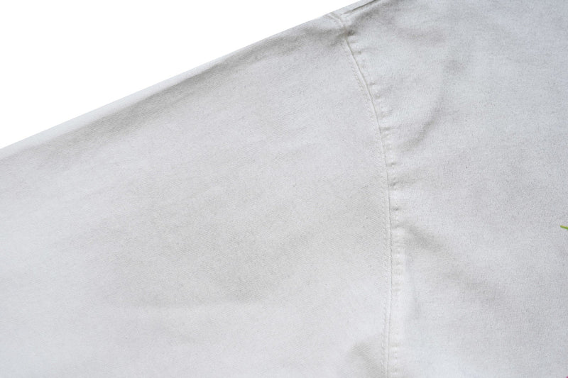Close-up of a white graphic T-shirt seam with subtle fabric texture and minimalist streetwear style