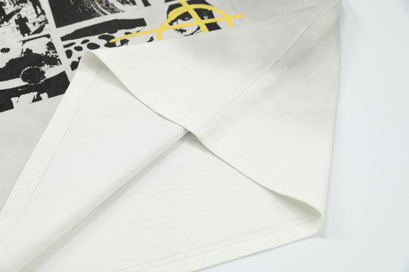 Close-up of an oversized cream graphic T-shirt with black collage panels and a yellow accent print