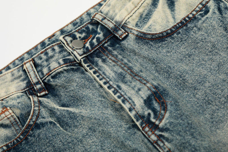 Close-up of light wash jeans front pocket, button fly area, and orange stitching