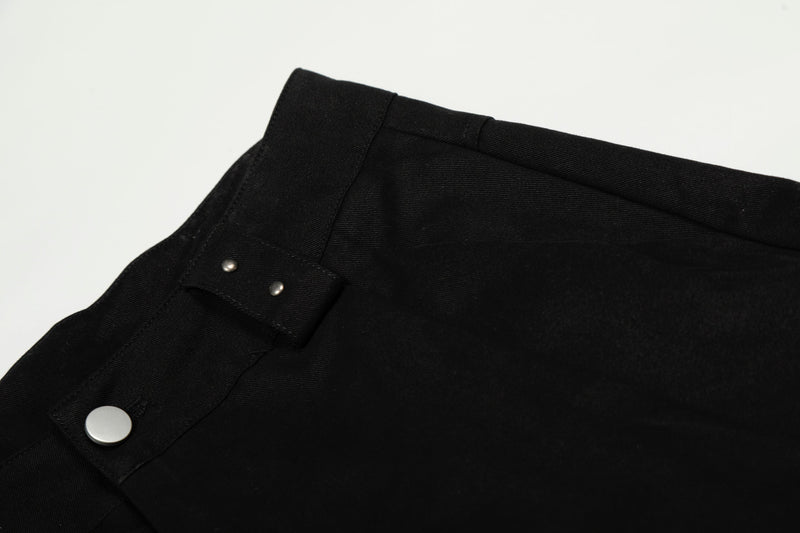 Close-up of black waistband corner with metal snap button and stitching