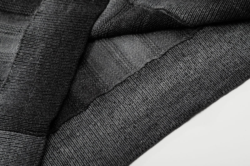 Close-up of a black open-knit polo shirt with gradient stripe texture and relaxed fit fabric details