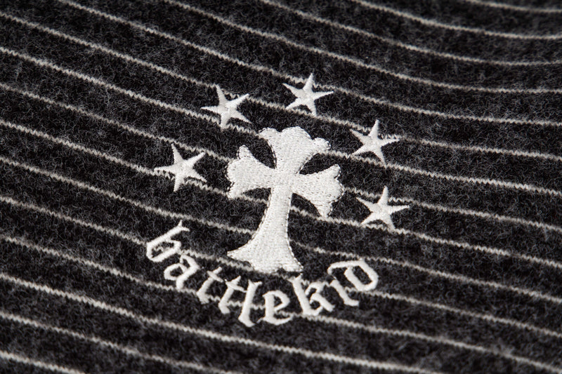 Close-up of black striped knit back chest logo with star and cross motif