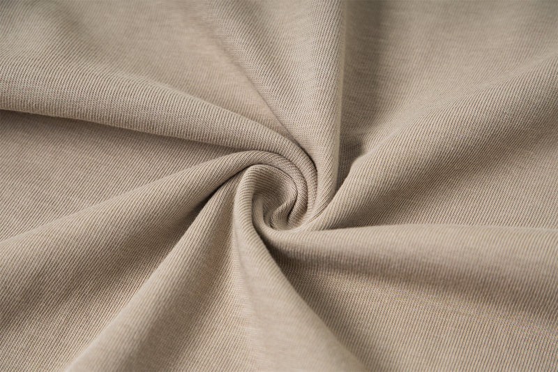 Close-up of beige fabric texture with soft folds and knit weave