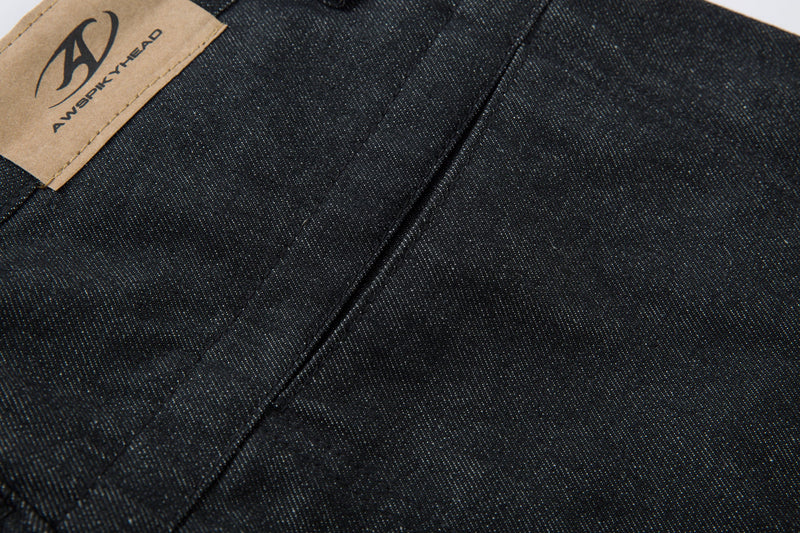 Close-up of dark denim seam and tan logo patch at the back waistband