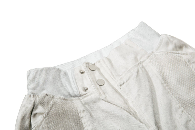 Close-up of the waistband and front snaps on light gray moto panel denim shorts