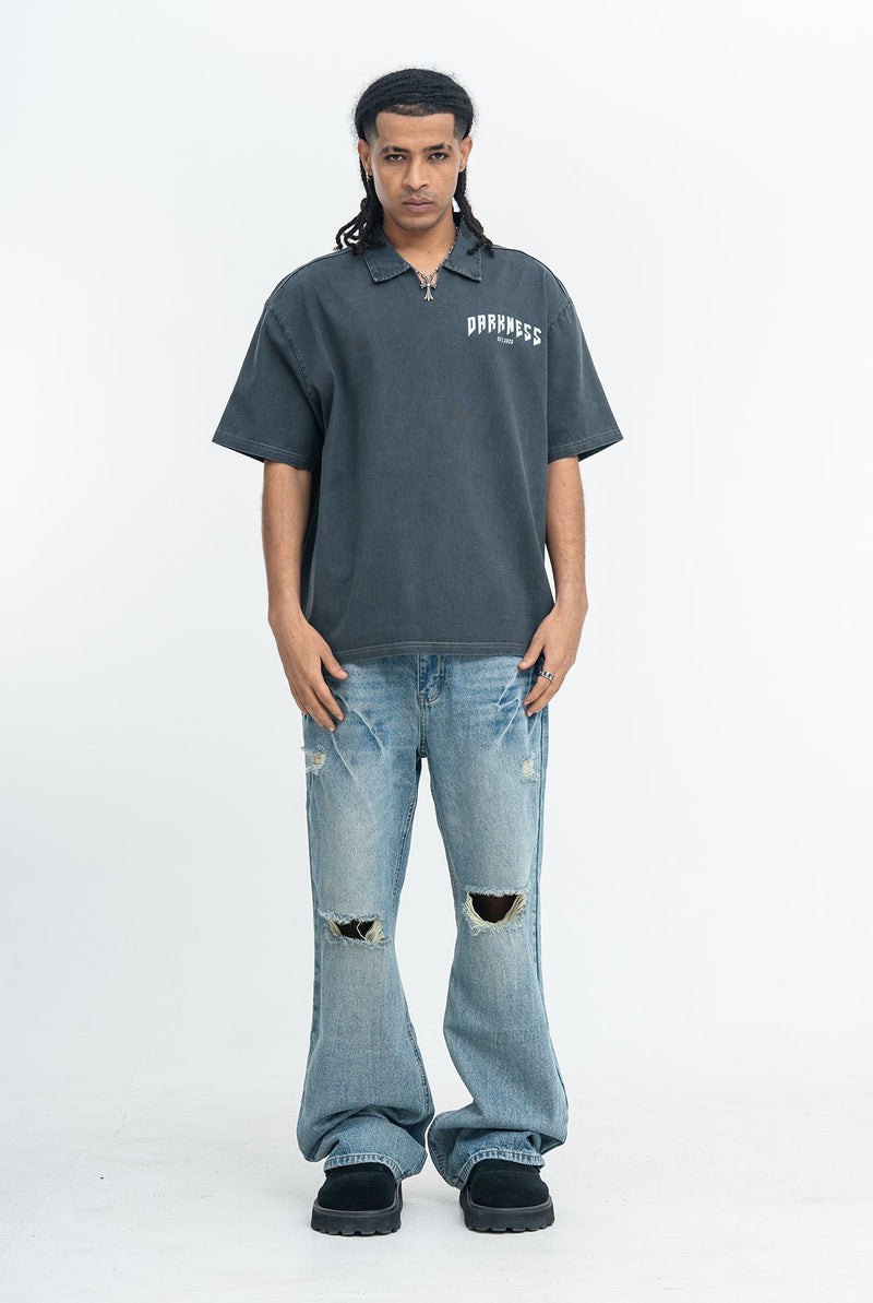 Model wearing a washed dark polo shirt with a small Darkness logo, paired with ripped wide-leg jeans and black shoes