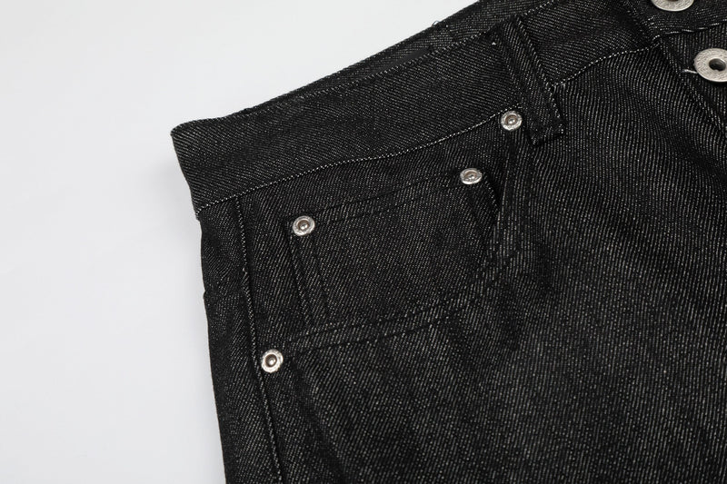 Close-up side view of black denim waist, button fly, and pocket edge