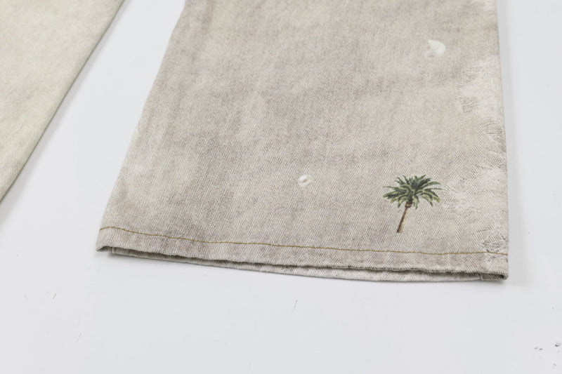 Close-up of lower hem on washed botanical print jeans with small palm tree detail