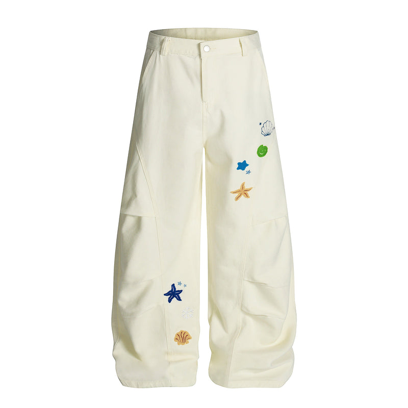 Front view of cream wide-leg cargo pants with shell, starfish, and blue-green embroidery