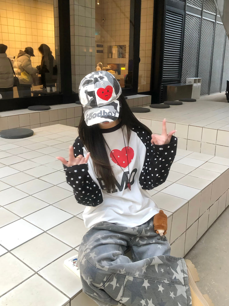 Model wearing white raglan long sleeve tee with black star-print sleeves and I Love EMO graphic