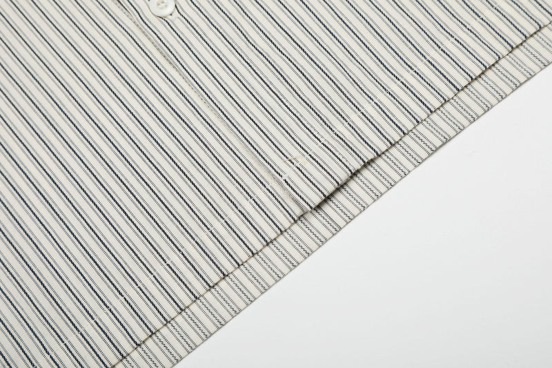Cream pinstripe button-up shirt with diagonal navy stripes and stitched detailing, shown in a close-up fabric view