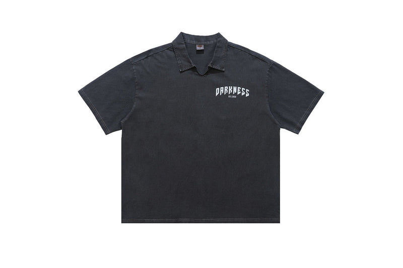 Black washed polo shirt with short sleeves and small chest logo, featuring a relaxed fit and dark vintage finish