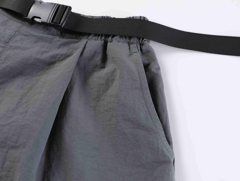 Close-up of gray shorts belt and gathered waistband from a side angle