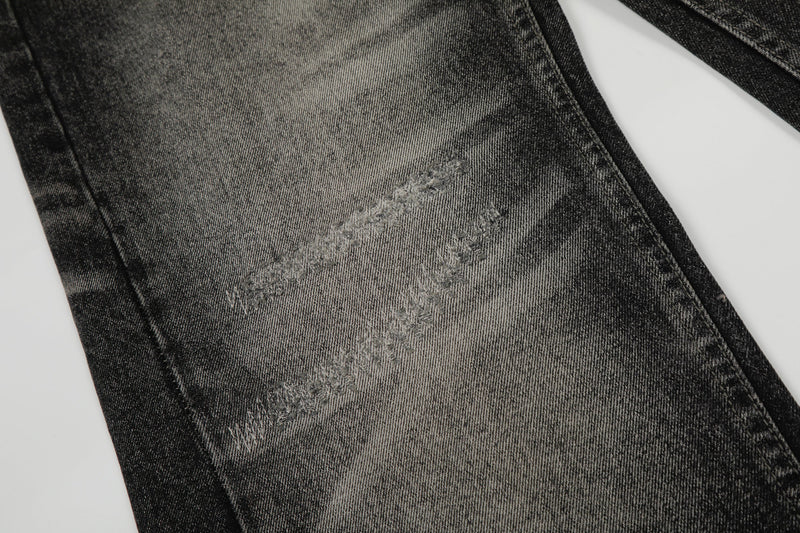 Close-up of distressed denim panel with faded gray wash and stitched marks