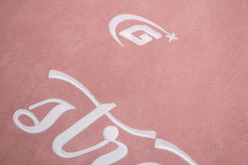 Pink suede-textured streetwear T-shirt with white embroidered athletic logo detail and soft panel design