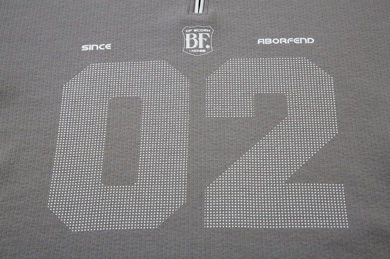 Close-up of gray polo back with chest logos and dotted 02 print