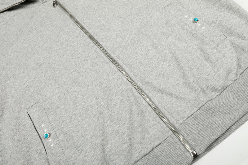 Close-up of light gray zip hoodie front with pocket and dot detail