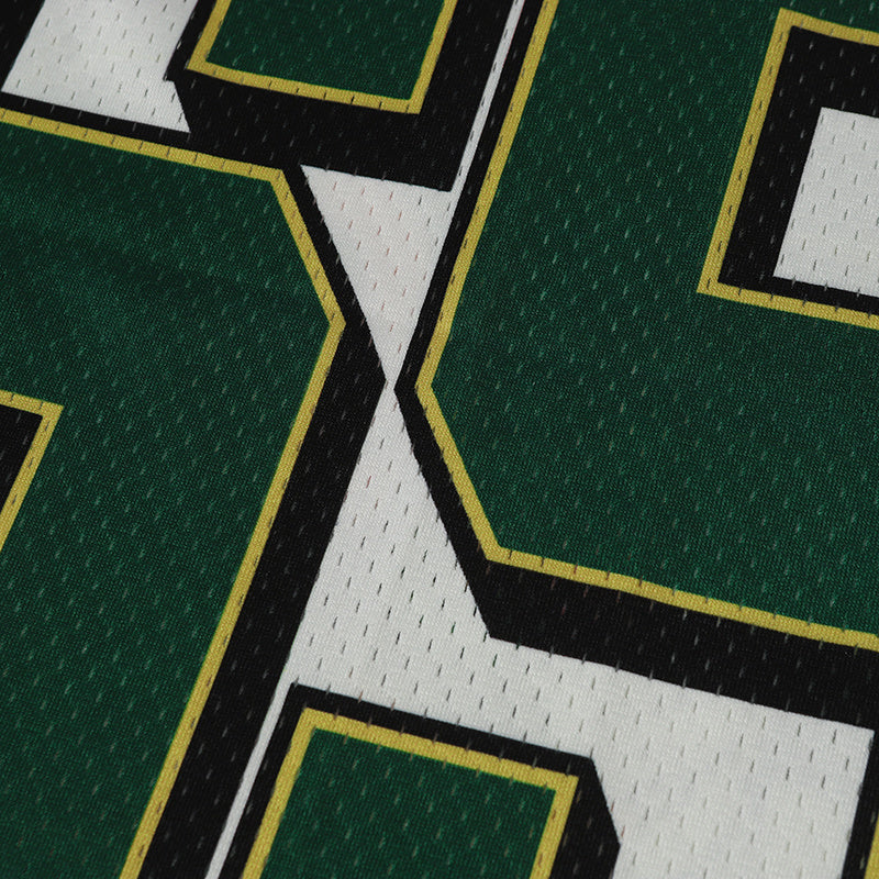 Close-up of a green varsity football jersey with bold white, black, and gold outlined lettering on mesh fabric