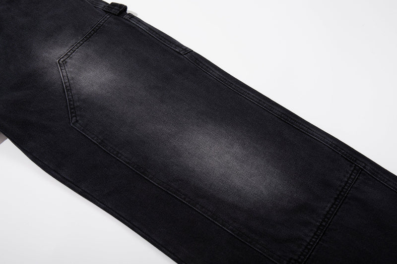 Close-up of black denim leg with curved seam detail and faded wash