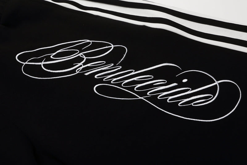 Close-up of black shorts front with white script graphic and side stripes