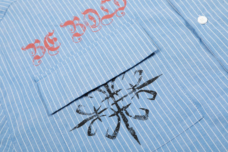 Close-up of blue striped shirt pocket, red text print, and black graphic symbol