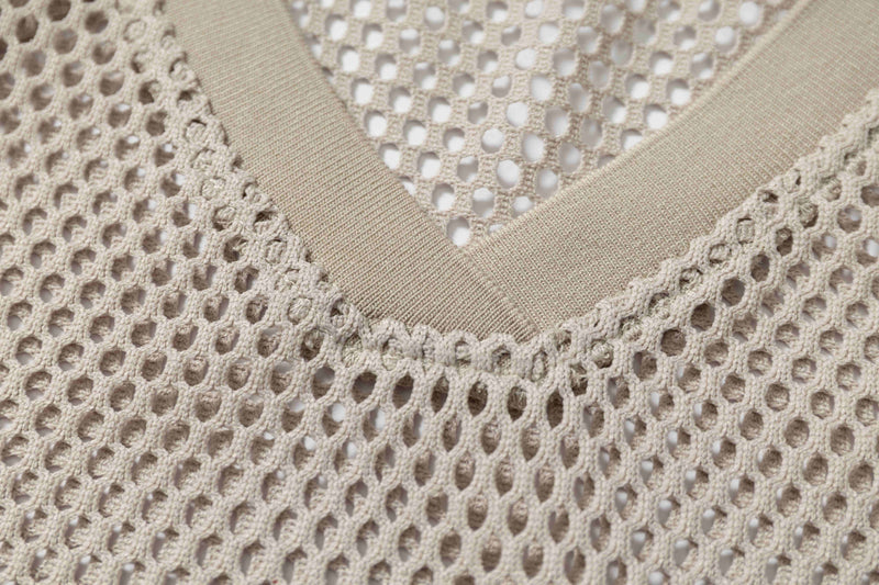 Close-up of a beige mesh football jersey tee with V-neck trim and retro oversized streetwear texture
