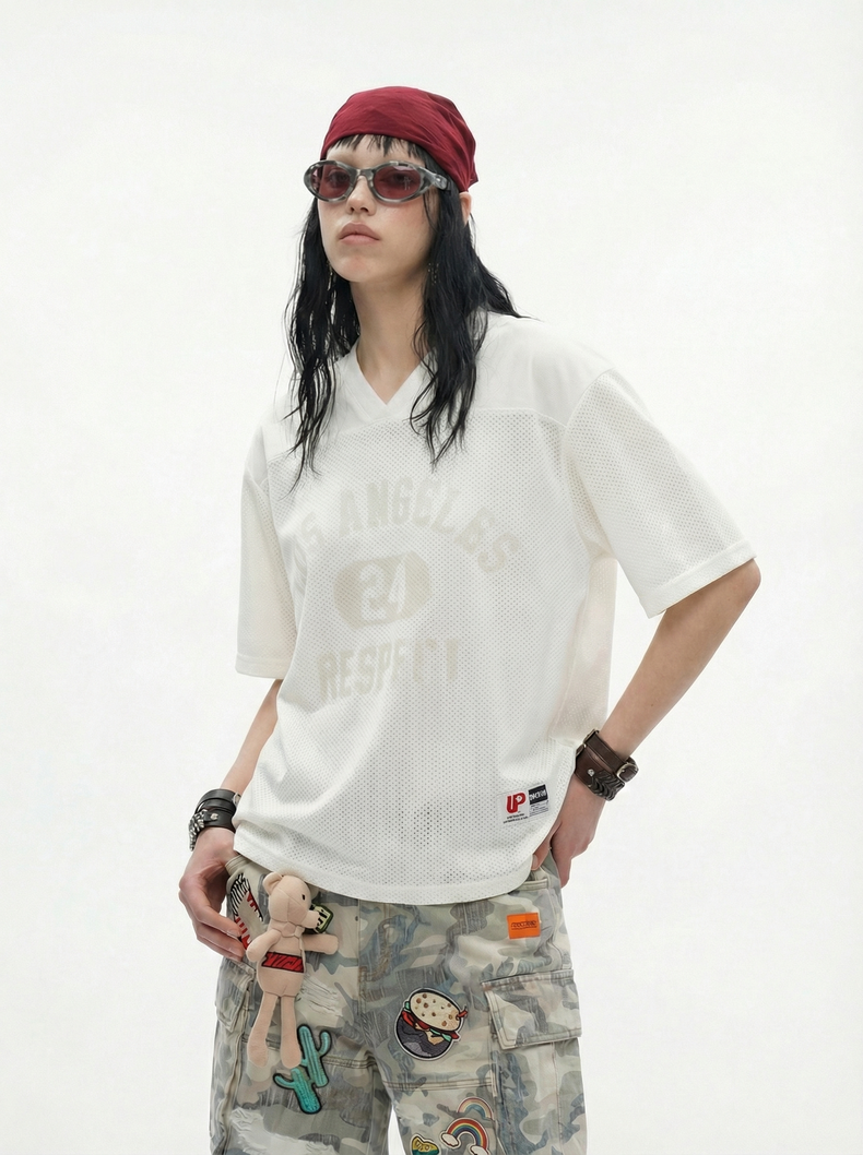 Model wearing a white mesh V-neck tee with faded Los Angeles 24 Respect print, paired with camo cargo pants and red headscarf