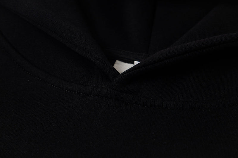 Close-up of black hoodie neckline showing layered hood seam and inner label
