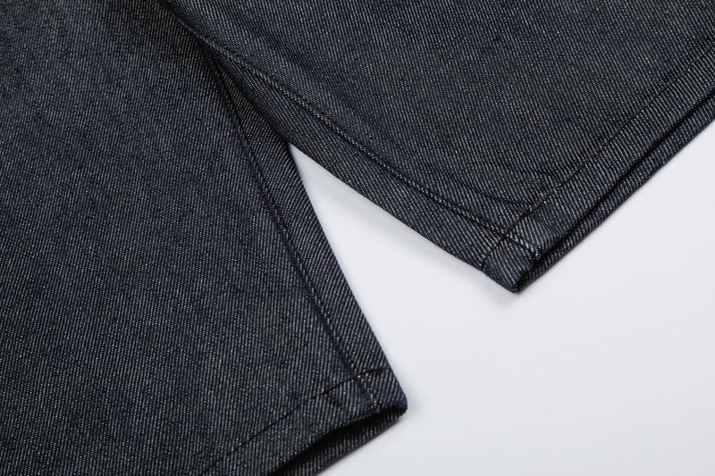 Close-up of folded raw hem and side seam on dark wash denim jorts