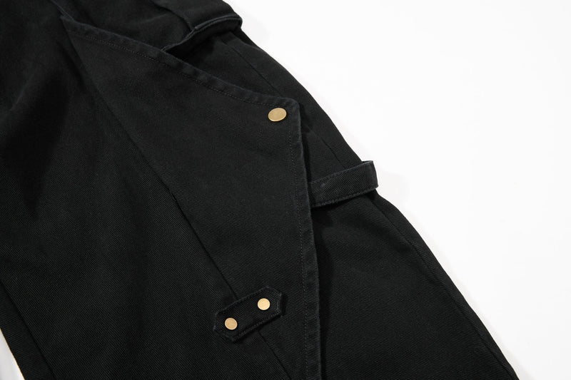 Close-up of black cargo pant side pocket flap with gold snap hardware