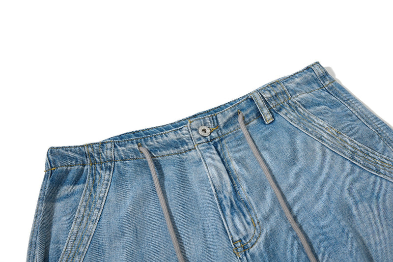 Close-up of light wash jeans waistband with drawstring, belt loop, and top button detail