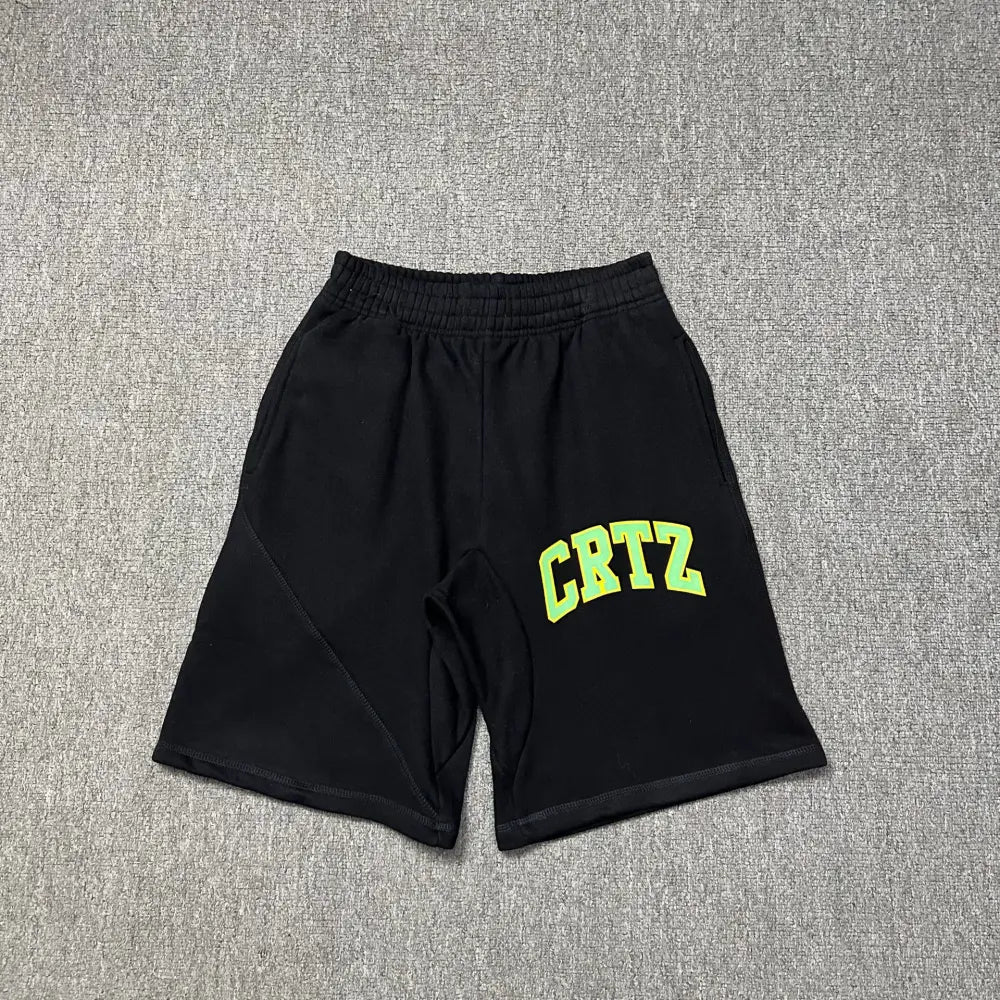 Black Corteiz jogger shorts laid flat, showing green and yellow arched CRTZ letter print on the front