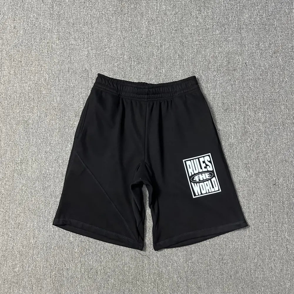 Black Corteiz jogger shorts laid flat, showing a white Rules The World graphic print on the left leg and an elasticated waistband