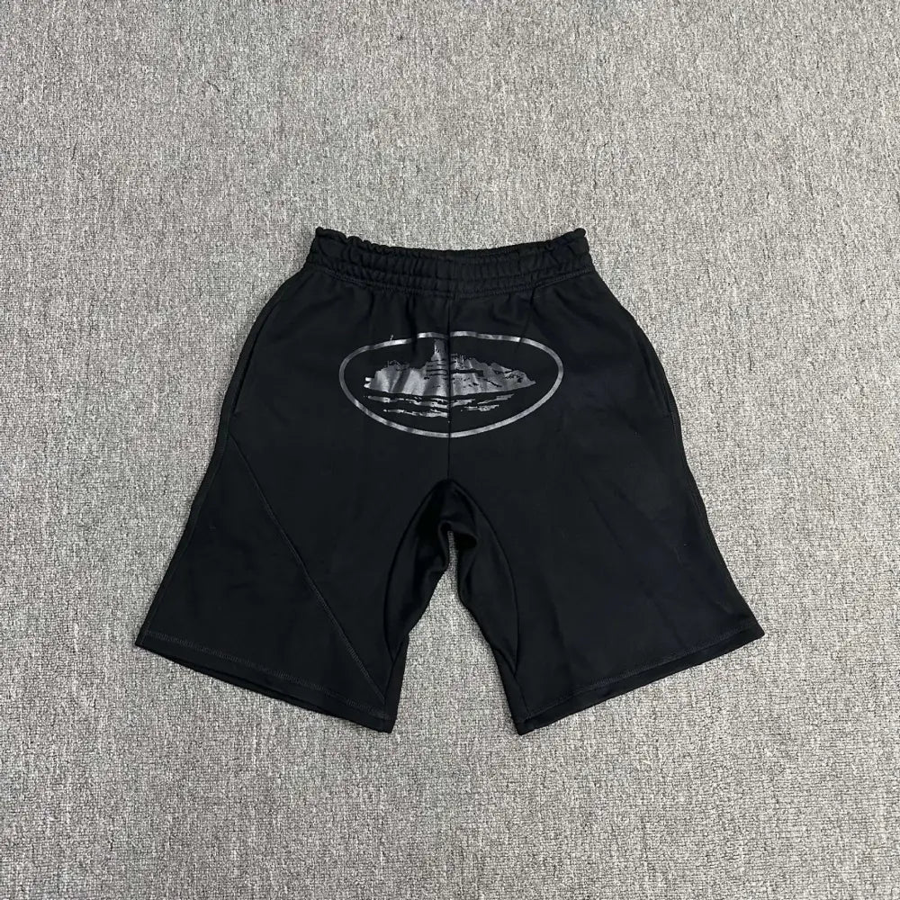 Black Corteiz jogger shorts laid flat, showing a tonal oval logo graphic print on the front and an elasticated waistband