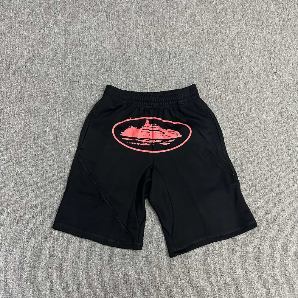 Black Corteiz cotton shorts laid flat, showing a large pink oval graphic print on the front panel