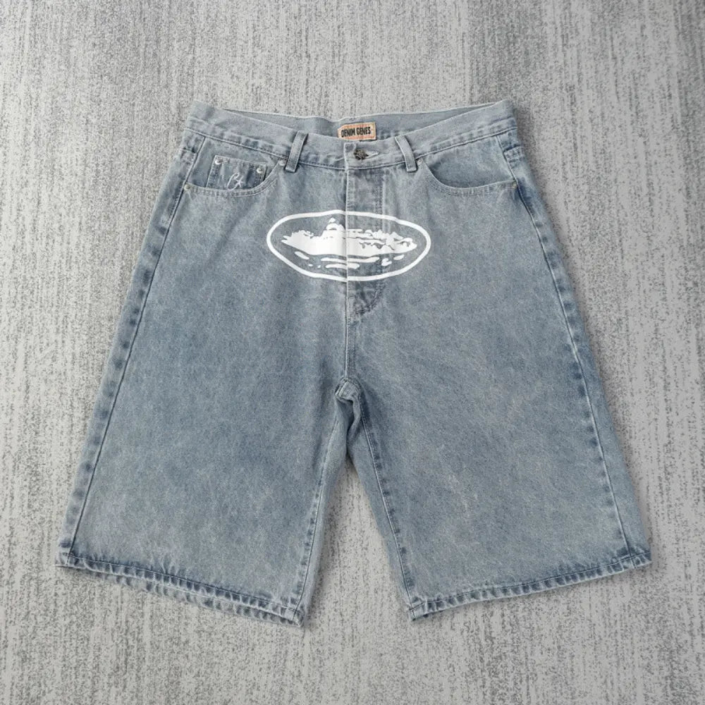 Corteiz light blue denim shorts laid flat, showing white oval graphic print on the front and five-pocket construction