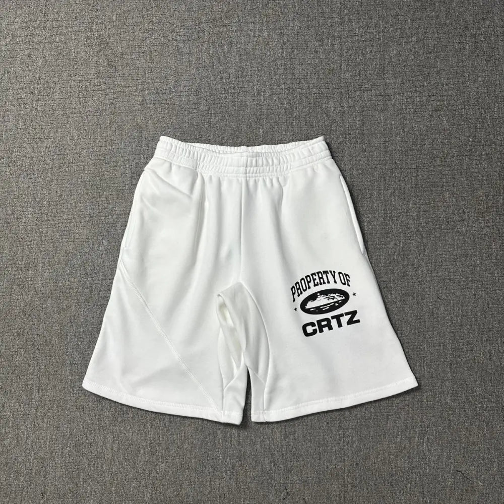 White Corteiz jogger shorts laid flat, showing black Property of CRTZ graphic print on the left leg