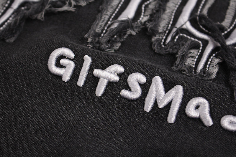 Close-up of black distressed graphic T-shirt with raised silver embroidered lettering and frayed star patch details