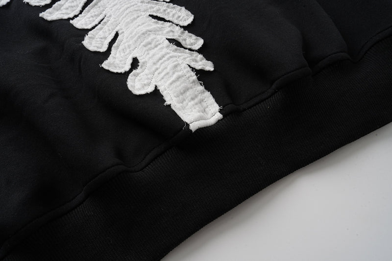 Close-up of white skeleton bone detail near the lower back of black hoodie