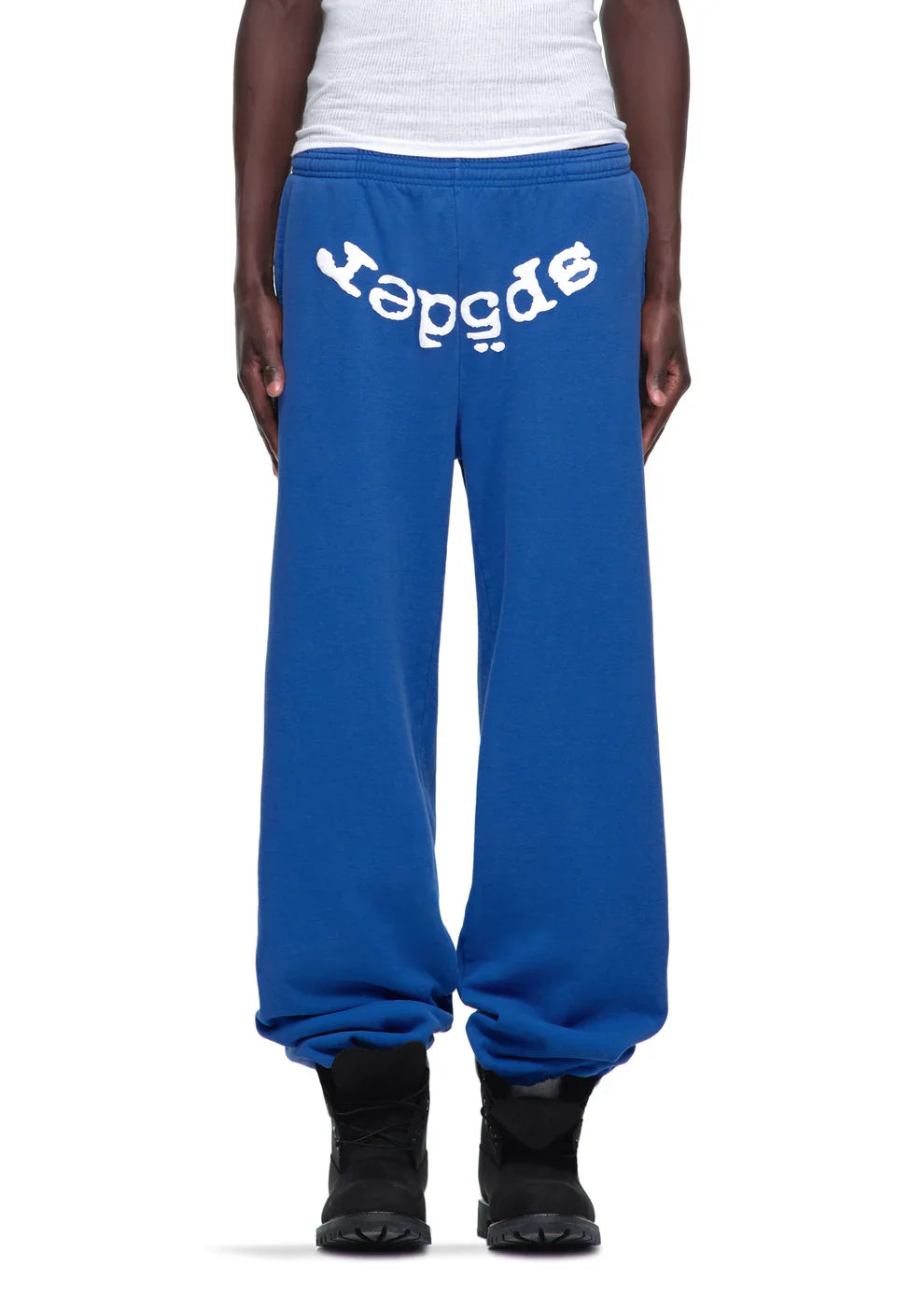Someone styled Sp5der Sweatpants – Unisex Blue Cotton Sweatpants with a bold front logo print, pairing them with black shoes and a white tank top for a cool streetwear vibe.