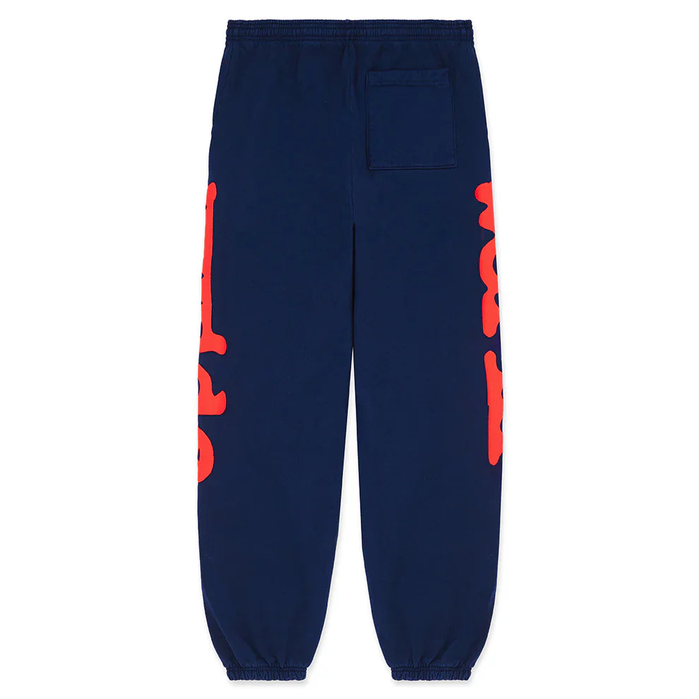The Sp5der Sweatpants Navy Blue Red Side Logo Print are 100% cotton jogger pants featuring elastic cuffs and waistband, a single back pocket, and bold red logo graphics running vertically along both outer legs—essential streetwear style.